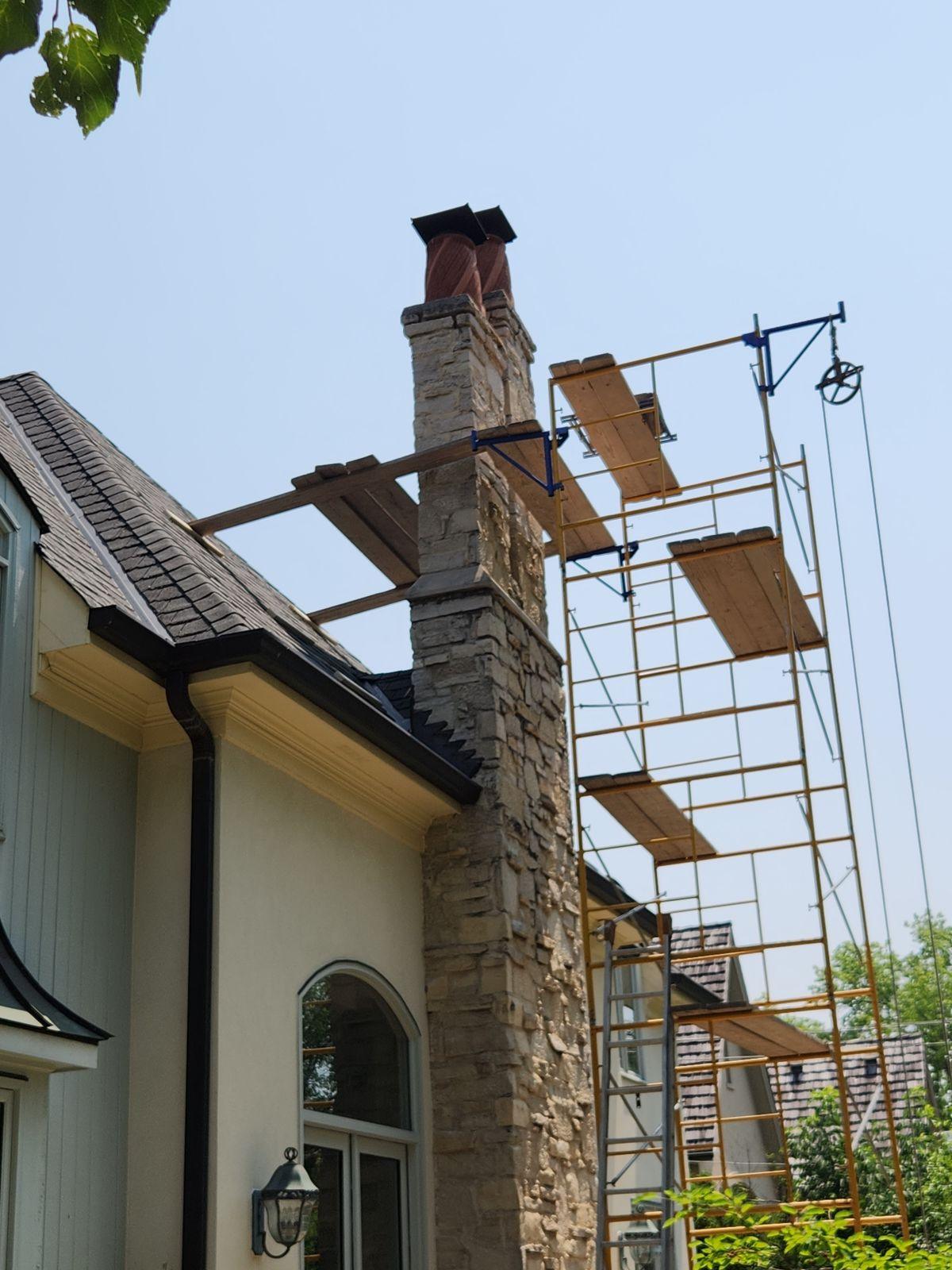 Stone chimney repair. Stone chimney work from scaffolding.