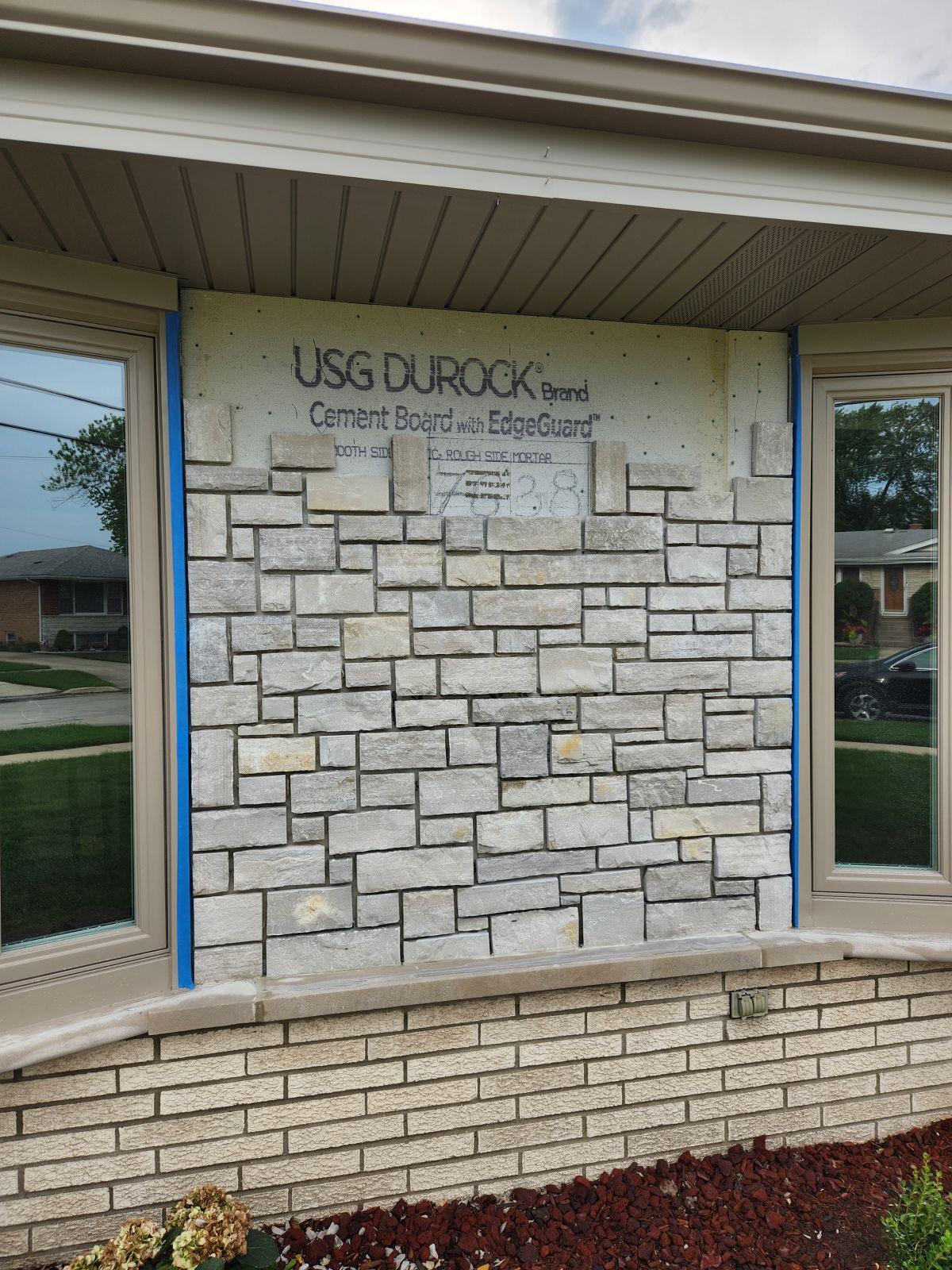 Stone veneer, in progress. Stone going up over cement board below a front window.